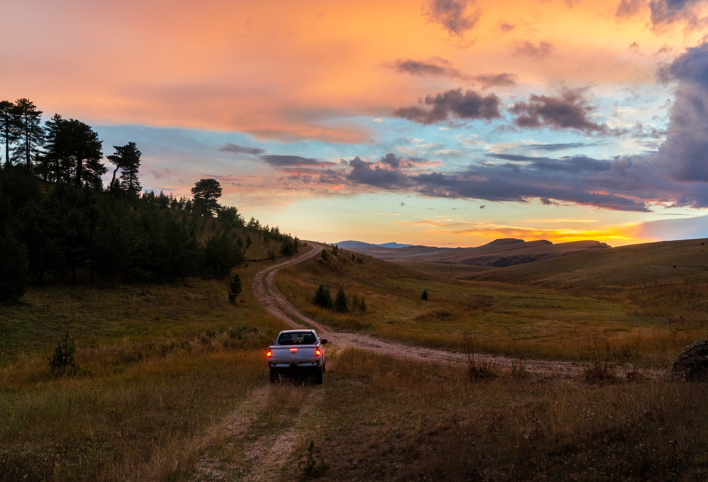 Pick-up truck on country road at sunset