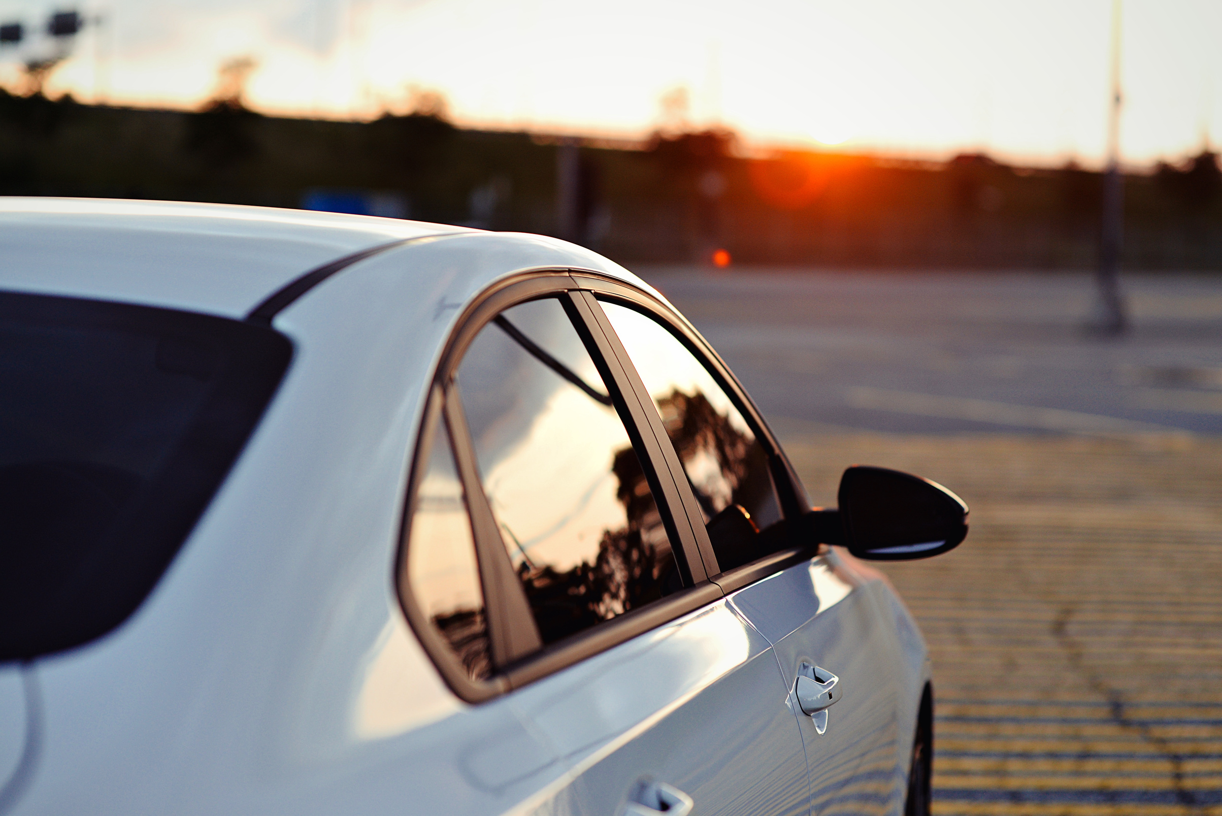 Beautiful sedan parked for a photoshoot with the sun setting against its darkened vinyl tinted windows.